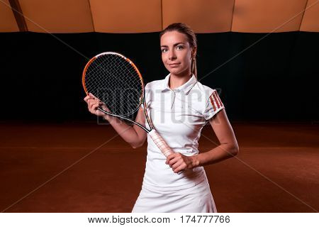 Sportswoman at the tennis court with racquet. Indoor tennis court