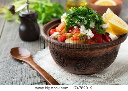 Fresh Salad Shopska of baked peppers tomato onion cucumber parsley dill and feta cheese in a ceramic bowl. Traditional Serbian food. Selective focus.