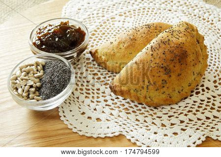 Russian pirozhki, baked patties or pies on basket with jam, sunflower seeds and poppy