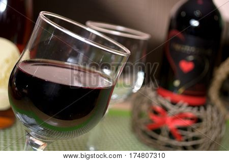Half full glass of fresh delicious red wine with blurred bottle in the background.