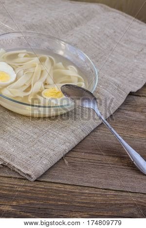 cup of chicken soup with noodles and eggs and pita bread