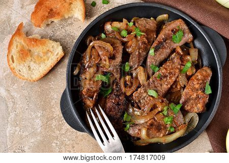 Fried liver with onions and apples on a concrete background
