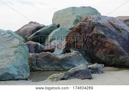huge old stones scattered on the beach of sea