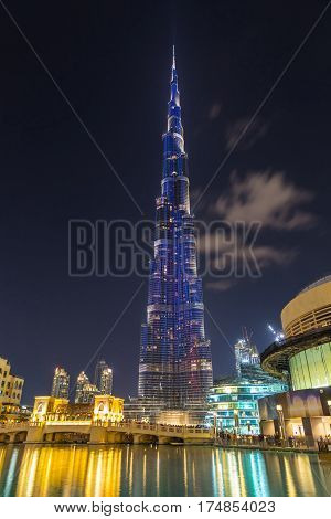 DUBAI United Arab Emirates (UAE) - 18 February 2017. Illuminated tower Burj Khalifa against the dark sky with clouds at night. Reflection of lights in the water. Highest in the world skyscraper (828 m)