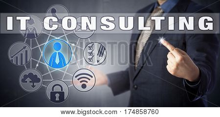 Male corporate advisor in blue business suit is activating IT CONSULTING onscreen. Information technology metaphor and business concept for IT advisory services and computer consultancy.