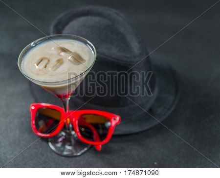 colored drink a combination of red beige and violet martini glass red sunglasses black stylish hat party set