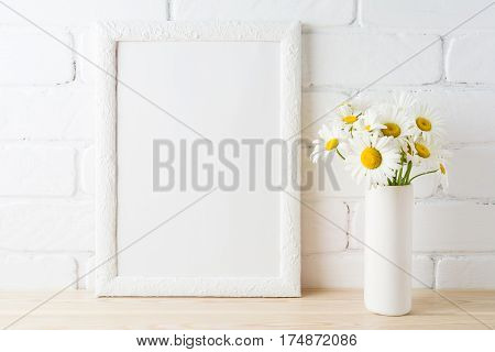 White frame mockup with daisy flower in styled vase near painted brick wall. Empty frame mock up for presentation design. Template framing for modern art.
