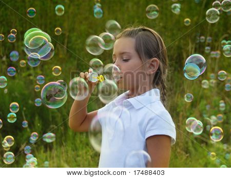 Dziewczynka dmuchanie baniek mydlanych na zachodzie słońca