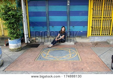 Traveller thai woman sit and portrait at front of colorful steel door roll shutter at home in George Town and street art area in Penang Malaysia