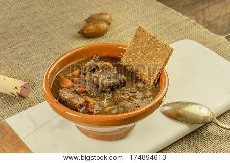 Meat and vegetable stew in an earthenware bowl, with a flatbread and a wine cork