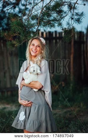 the pregnant girl with a hat in the field of wheat on a sunset