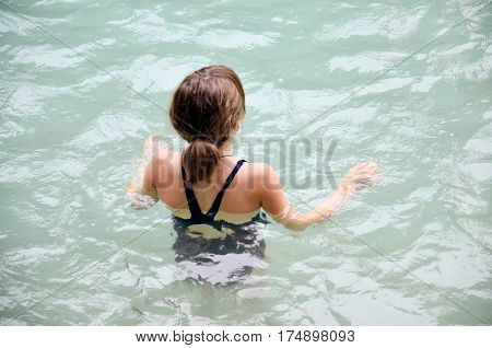 Traveller children girl playing and swim in pond of Kuang Si Falls or Tat Kuang Si Waterfalls in Luang Prabang Laos
