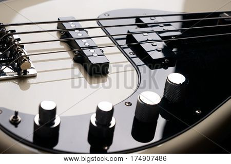 Black and white electric bass guitar close up.Black background.
