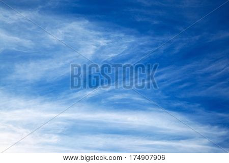 White spindrift clouds on blue sky background