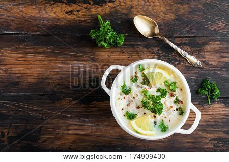 Avgolemono, Chicken Soup With Egg-lemon Sauce, Rice And Fresh Parsley Leaves In White Bowl On Wooden