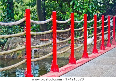 pedestrian bridge built in art wooden red railing and hemp ropes in the park of Pinocchio in Italy