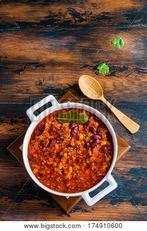 Traditional Polish cuisine stewed Breton beans with minced beef bacon mashed tomatoes onion garlic paprika bay leaves and spices. White casserole on wooden rustic table top view.