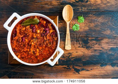 Traditional Polish cuisine stewed Breton beans with minced beef bacon mashed tomatoes onion garlic paprika bay leaves and spices. White casserole on wooden rustic table top view.