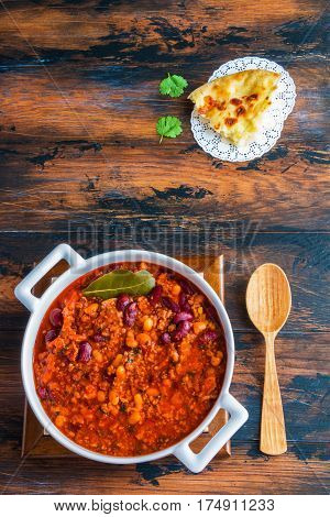 Traditional Polish cuisine stewed Breton beans with minced beef bacon mashed tomatoes onion garlic paprika bay leaves and spices. White casserole on wooden rustic table top view.