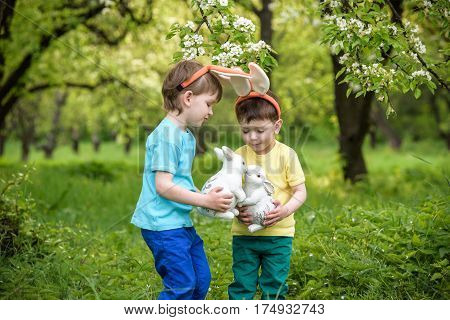 Two Little Kids Boys And Friends In Easter Bunny Ears During Traditional Egg Hunt In Spring Garden,