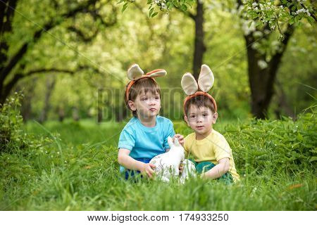 Two Little Kids Boys And Friends In Easter Bunny Ears During Traditional Egg Hunt In Spring Garden,