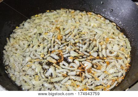 The process of frying the onions in a hot pan in vegetable oil