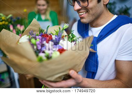 Guy smelling bouquet of flowers in florist store