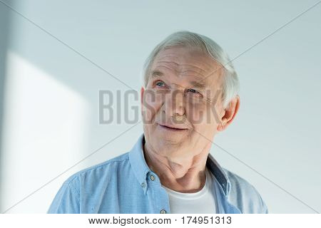 portrait of pensive senior man in stylish shirt on white