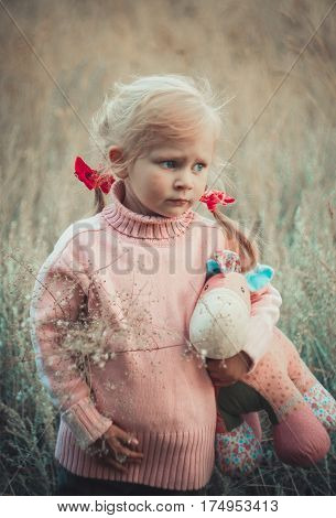 Adorable sad girl with hourse toy in park autom