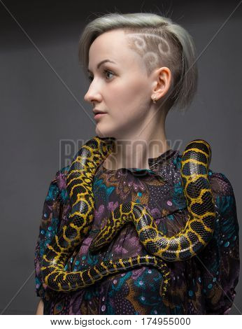 Blond woman and yellow reptile on gray background