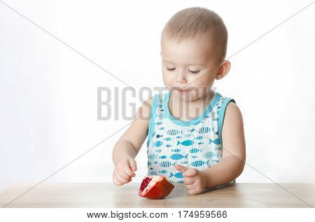 Baby eats a pomegranate ripe and juicy very tasty and joyfully