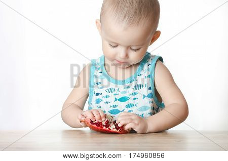 Baby eats a pomegranate ripe and juicy very tasty and joyfully