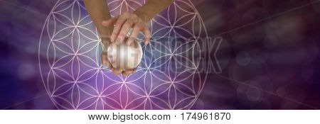 Sacred Geometry and Crystal Ball Scrying - Female holding a large crystal ball above a Flower of Life Symbol on a wide purple bokeh background with copy space