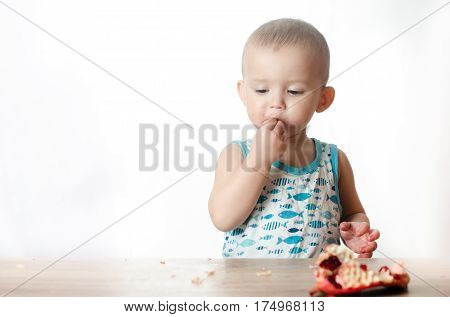 Baby eats a pomegranate ripe and juicy very tasty and joyfully