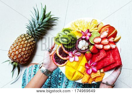 Hands holding served fruit plate, top view from above. Exotic summer diet. Tropical beach lifestyle.
