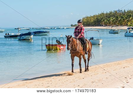 Le Morne Mauritius - December 11 2015: Woman ride horse on the Le Morne Beach one of the finest beaches in Mauritius and the site of many tourism facilities.