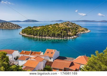 Small island in adriatic sea in summer. Red roofs clear water