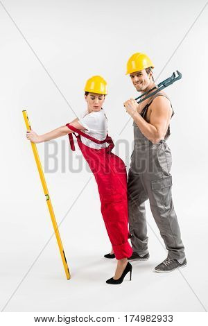 Young male and female builders posing with tools on grey