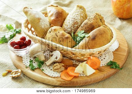 Russian pirozhki, baked patties or pies on basket with cheese and mushrooms
