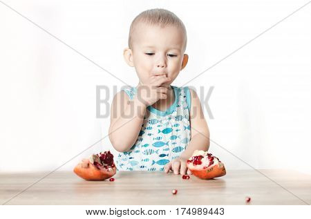 Baby eats a pomegranate ripe and juicy very tasty and joyfully