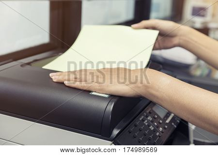 woman hands putting a sheet of paper into a copying device
