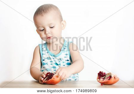 Baby eats a pomegranate ripe and juicy very tasty and joyfully