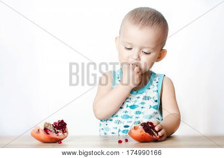 Baby eats a pomegranate ripe and juicy very tasty and joyfully