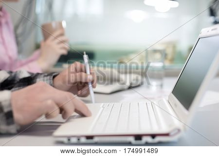 Modern Office Background View white portable Laptop and male Hands touching Keyboard - focus on Computer rear edge