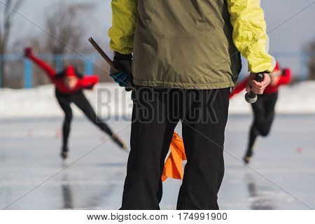 Speed skating competition - instructor and sportsmen on ice rink - children's sport concept, telephoto