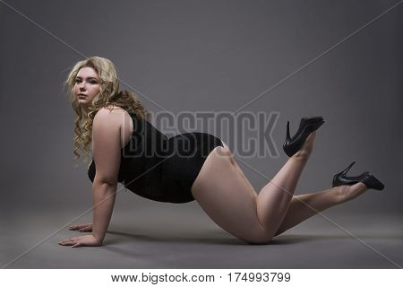Young beautiful blonde plus size model in shapewear xxl woman in slimming underwear on gray studio background full length portrait