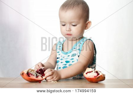 Baby eats a pomegranate ripe and juicy very tasty and joyfully