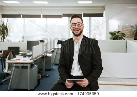 Bearded business man in eyeglasses and siut with tablet computer