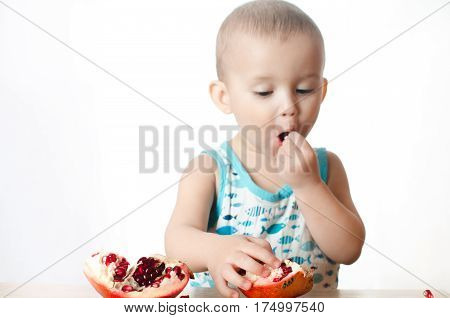 Baby eats a pomegranate ripe and juicy very tasty and joyfully