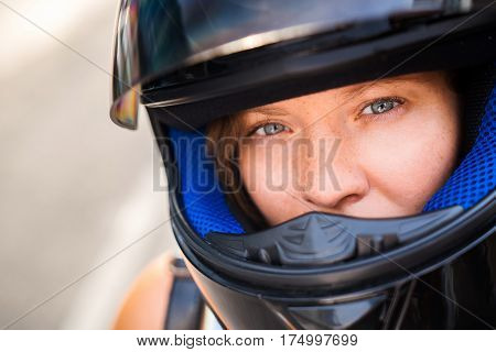 The concept of safe driving. Portrait of a girl with freckles close-up in a motorcycle helmet serious look into the camera.